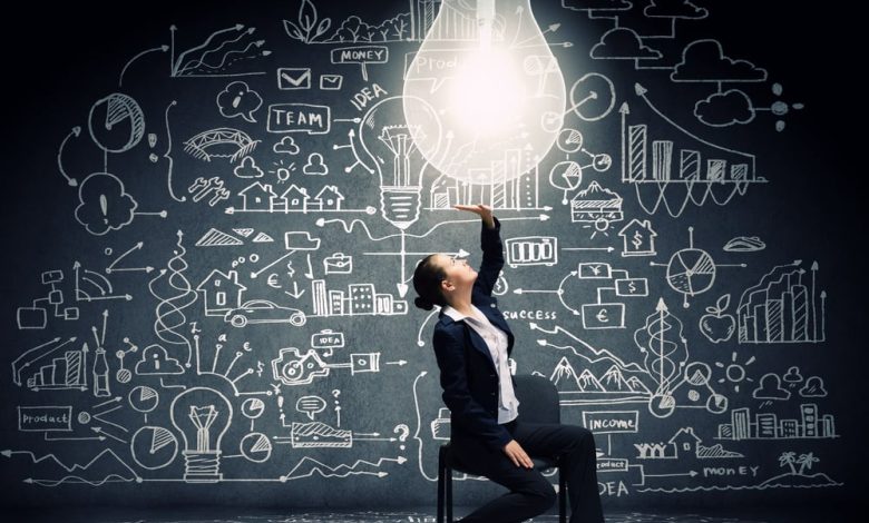Young businesswoman sitting on chair with big light bulb above